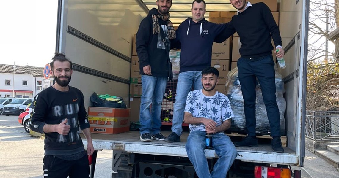 Geflüchtete aus Syrien helfen beim Beladen der LKWs 