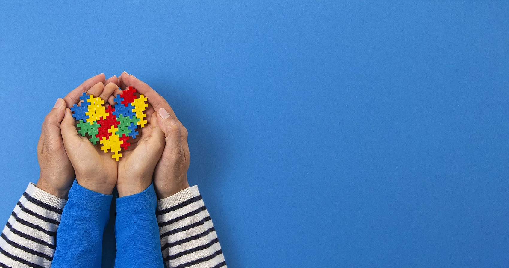 Symbolbild Kinderhände und Erwachsenenhände mit Puzzelsteinen