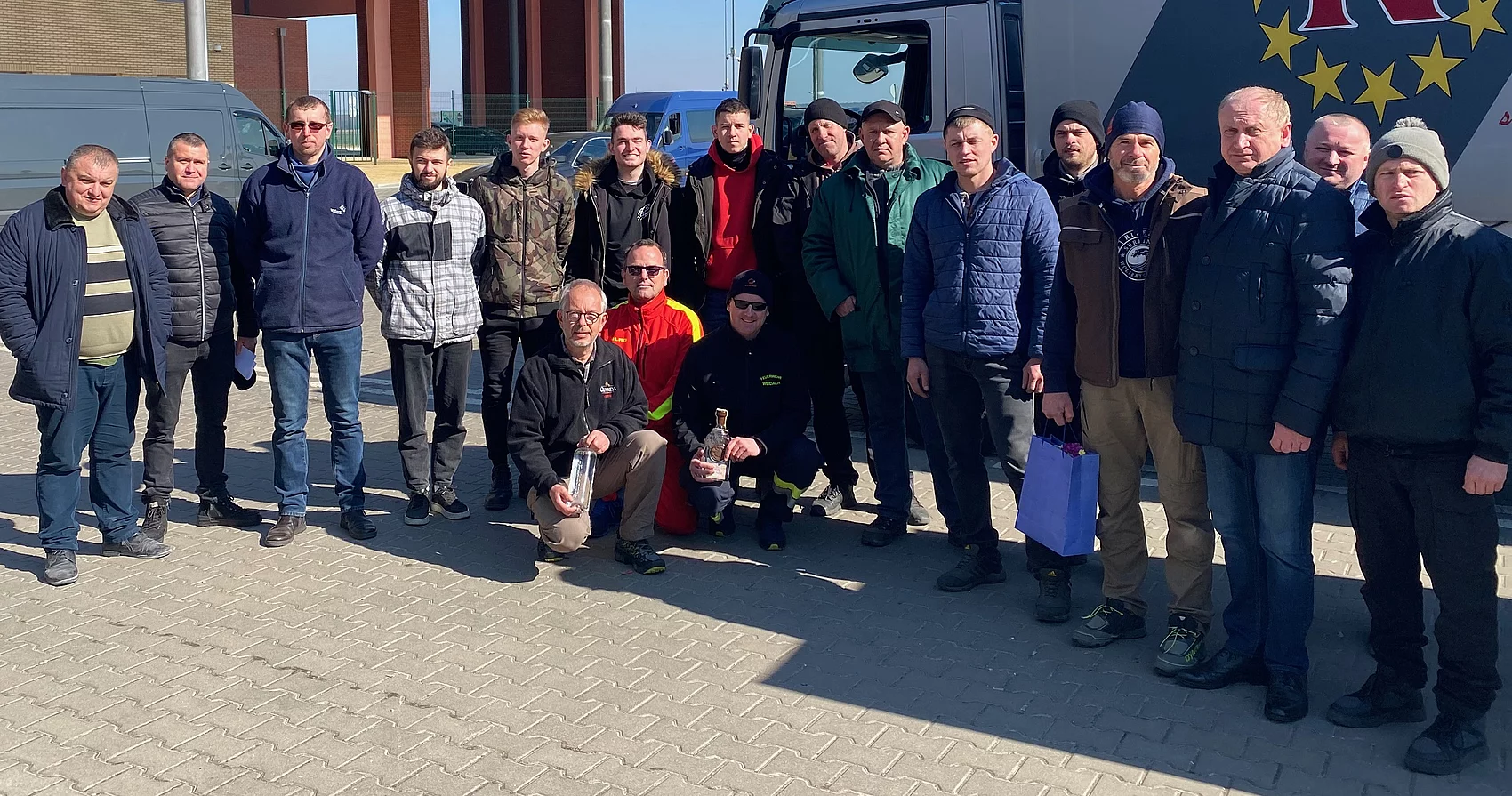 Gruppenbild mit Männern aus Brody und den Fahrers des Hilfstransports an der Grenze