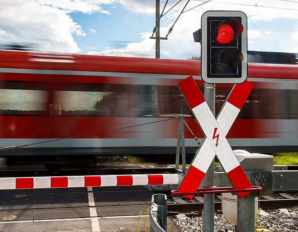 Symbolbild S-Bahn-Schranke geschlossen mit Zug im Hintergrund