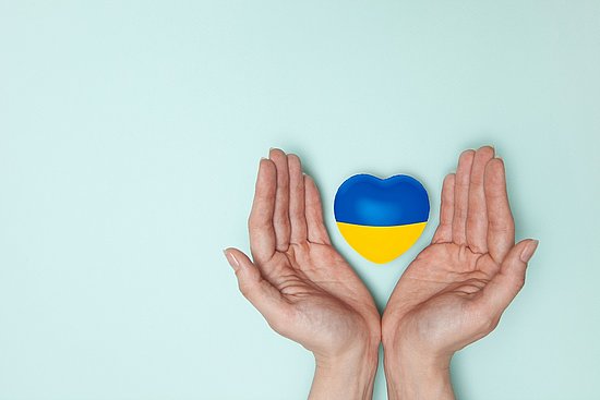 Symbolbild Hände mit einem Herz in Blau und Gelb, den Nationalfarben der Ukraine