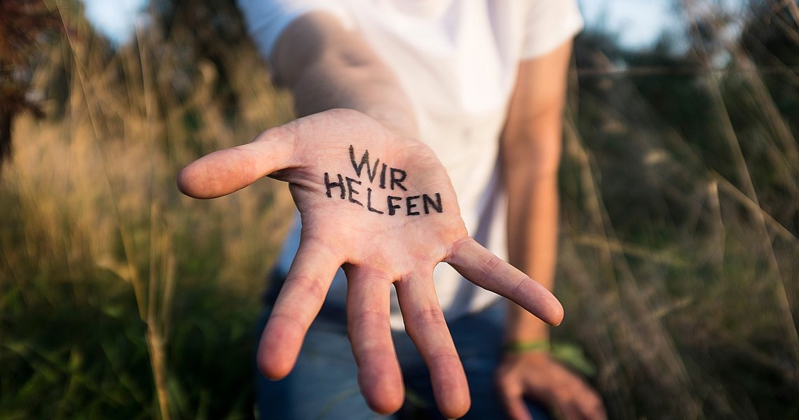 Symbolbild eine Hand auf der steht "Wir helfen"
