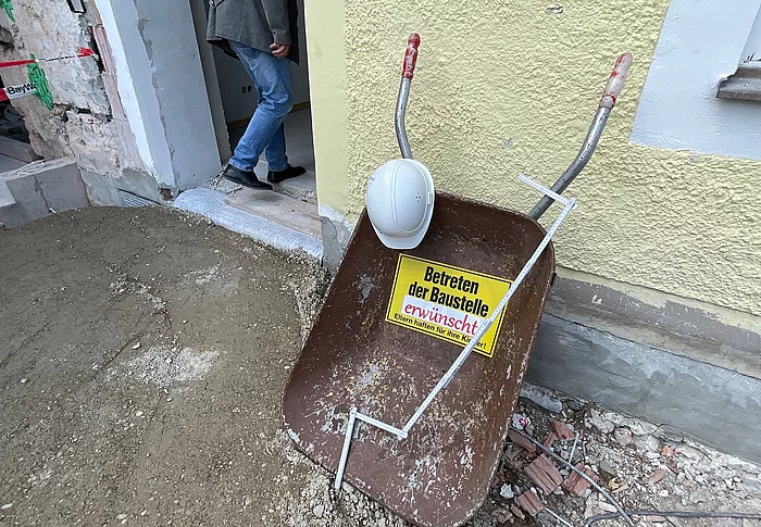 Schild und Schubkarren mit der Aufschrift Baustelle betreten erwünscht