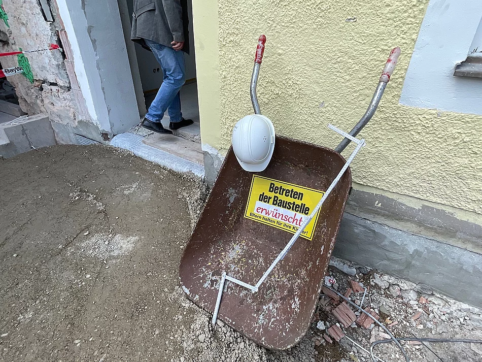 Schild und Schubkarren mit der Aufschrift Baustelle betreten erwünscht